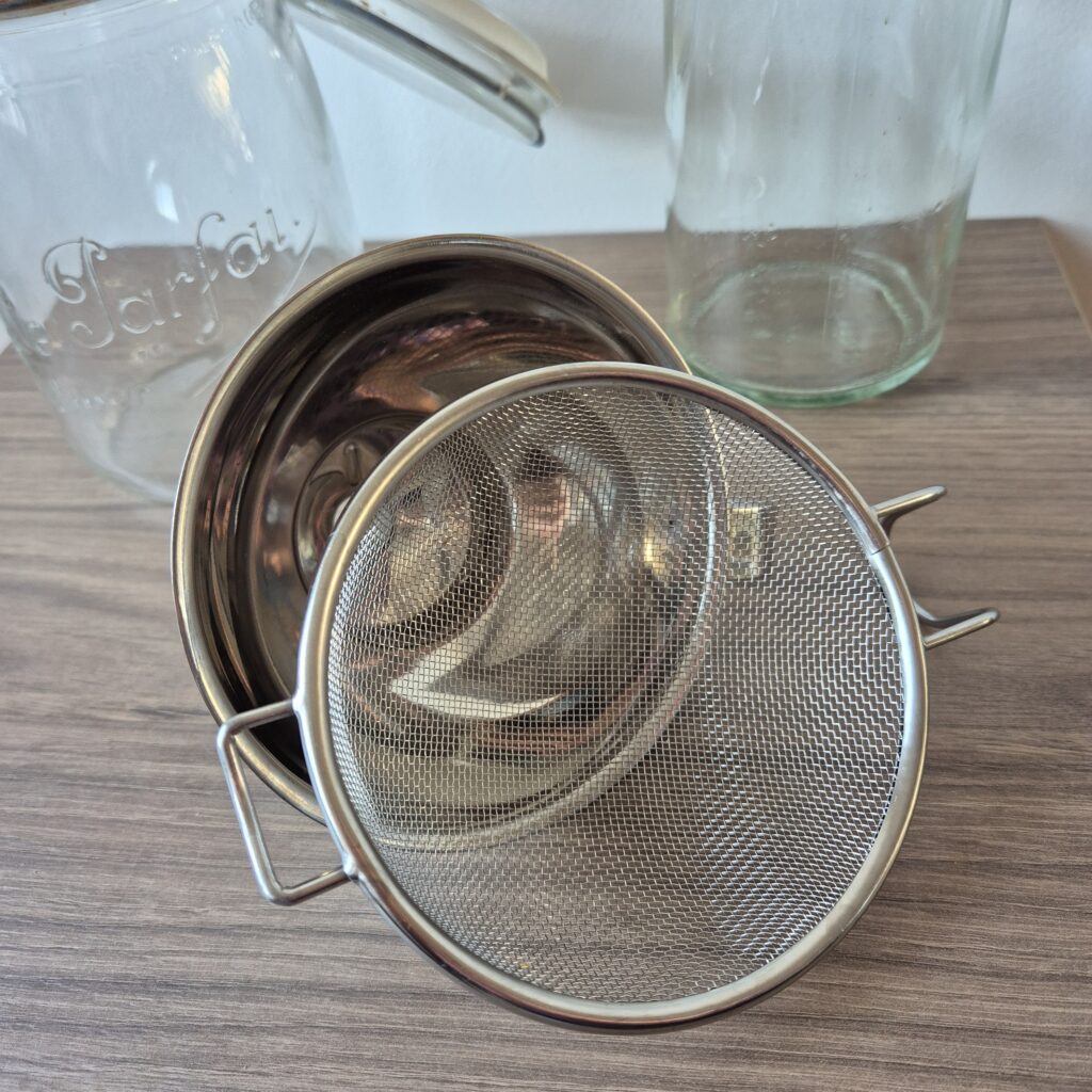 Le matériel indispensable pour réussir son tepache maison : un bocal en verre avec fermeture, un entonnoir avec passoire filtrante et une bouteille en verre